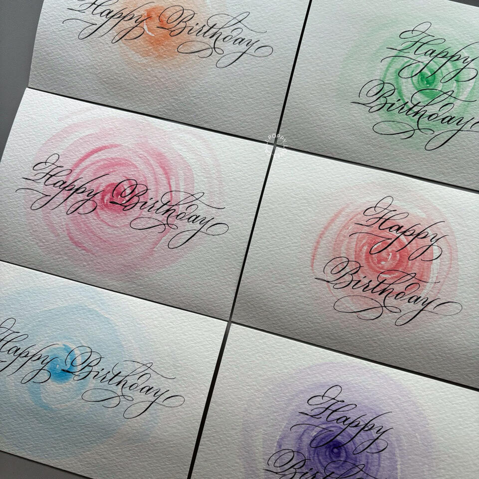 การ์ดสุขสันต์วันเกิด Happy Birthday เขียนในสไตล์ Calligraphy วาดดอกไม้ตกแต่งด้วยสีน้ำ ใส่ไว้ในซองจดหมายสีหวาน ตกแต่งรูปด้วยช่อดอกไม้สีชมพูแซมขาว